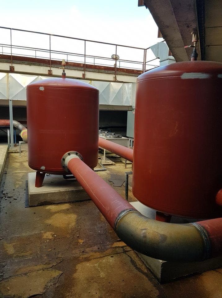 Deux vases d'expansion rouges raccordés en toiture d'immeuble