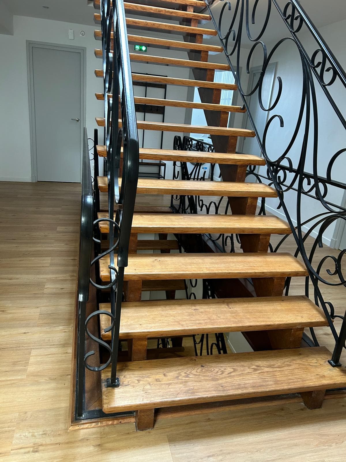 Escalier en bois massif avec garde-corps en fer forgé après rénovation